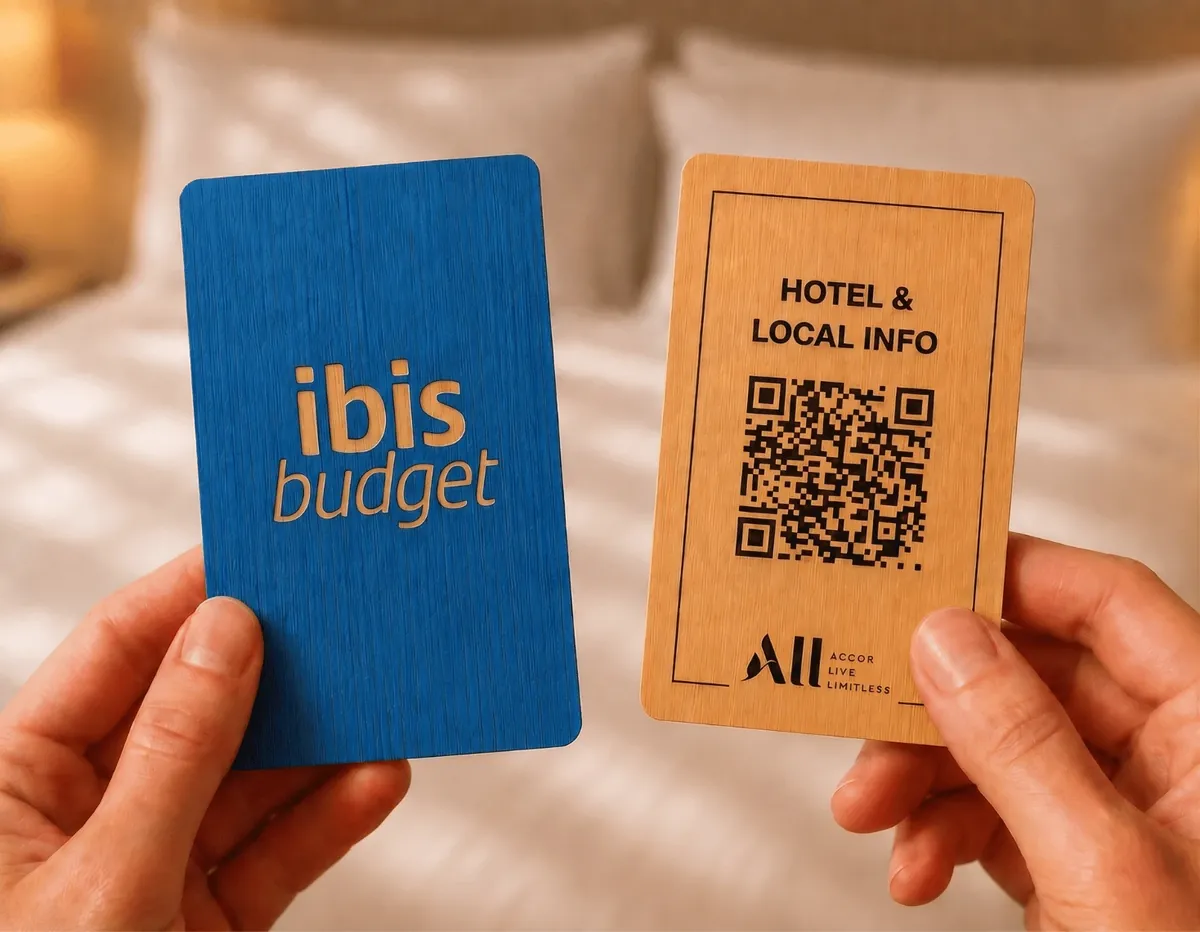 An engraved ibis budget wooden key card next to a wooden “Hotel & local info” card with a QR code